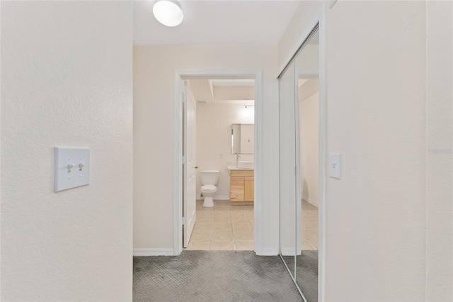 hallway with tile patterned flooring, baseboards, and carpet