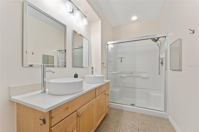 bathroom with a sink, double vanity, a shower stall, and tile patterned flooring