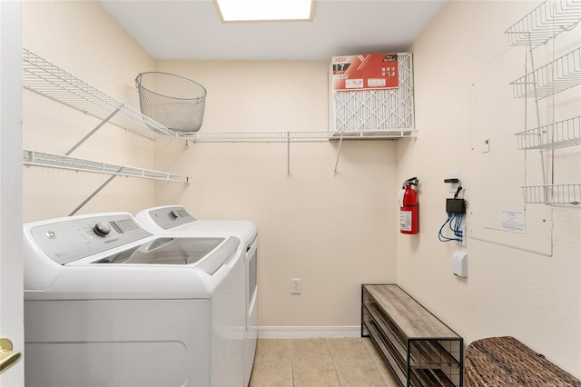 washroom featuring laundry area, light tile patterned floors, baseboards, and washer and clothes dryer