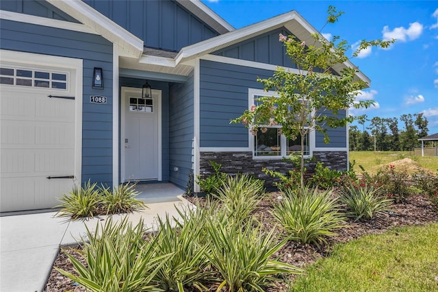 view of exterior entry featuring a garage, stone siding, and board and batten siding