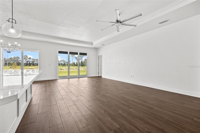 unfurnished living room featuring a tray ceiling, dark wood-style flooring, visible vents, and baseboards