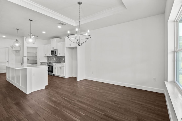 kitchen with dark wood-style flooring, ornamental molding, appliances with stainless steel finishes, decorative backsplash, and a tray ceiling