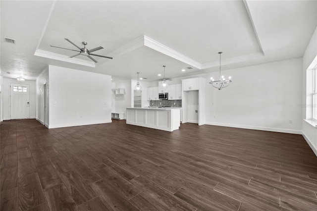 unfurnished living room featuring visible vents, a raised ceiling, dark wood-type flooring, and ceiling fan with notable chandelier