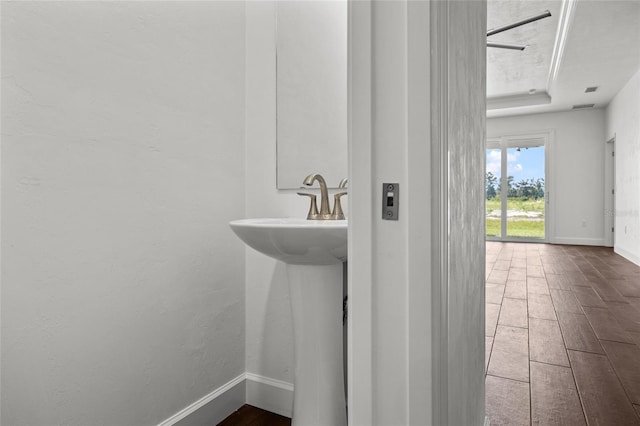 bathroom with baseboards, a tray ceiling, and wood finished floors