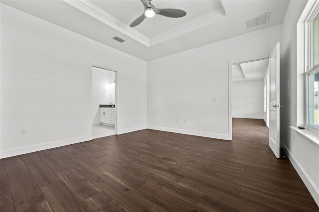 interior space with dark wood-style floors, a tray ceiling, ornamental molding, and visible vents