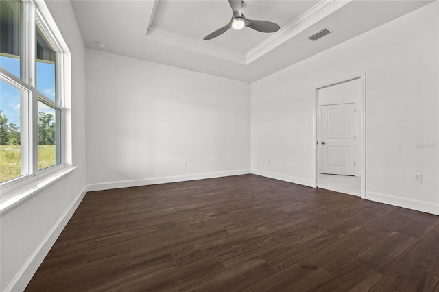 unfurnished room featuring visible vents, a tray ceiling, dark wood finished floors, and crown molding