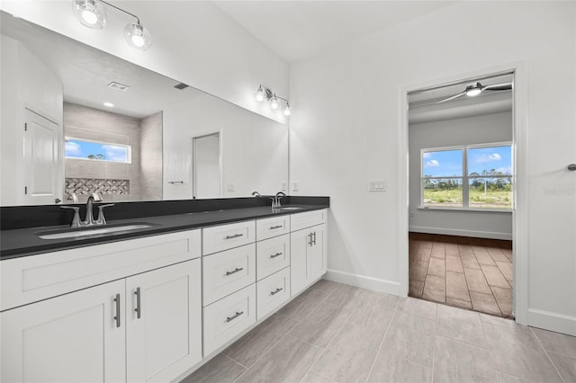 bathroom featuring double vanity, a wealth of natural light, baseboards, and a sink