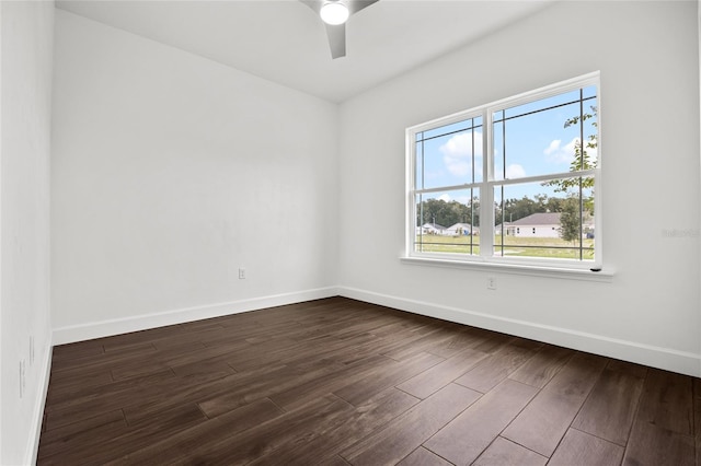 empty room featuring ceiling fan, dark wood finished floors, and baseboards