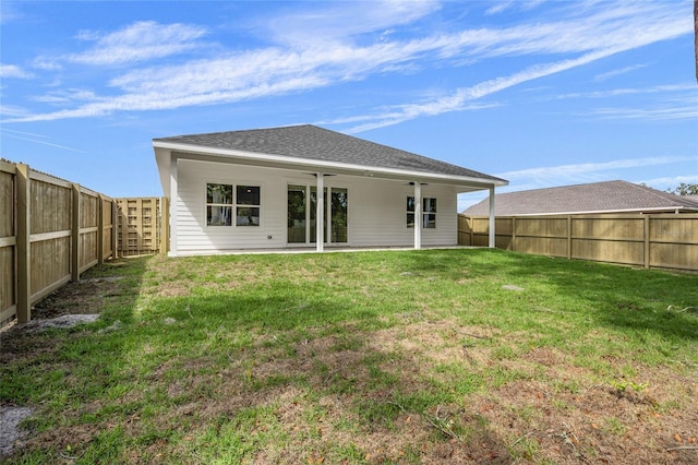 rear view of property featuring a fenced backyard, a shingled roof, and a lawn