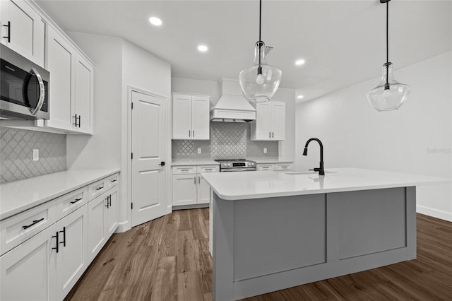 kitchen with dark wood-style floors, appliances with stainless steel finishes, custom exhaust hood, and a sink