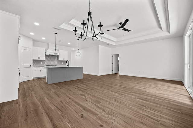 kitchen with tasteful backsplash, visible vents, a tray ceiling, and wood finished floors