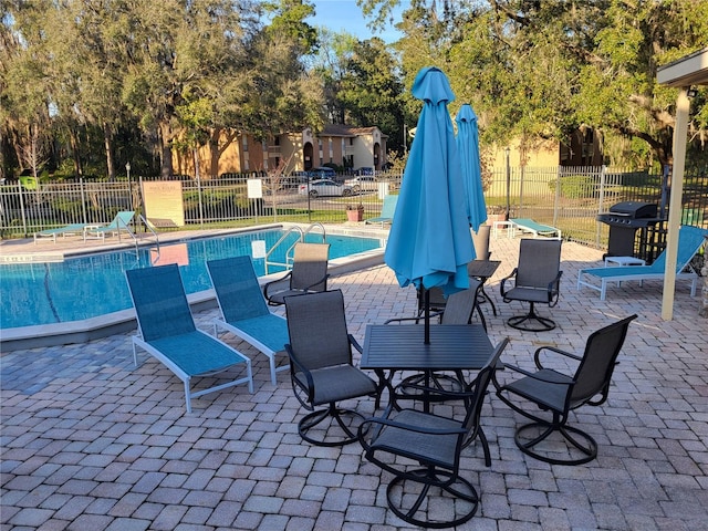 community pool with a patio, area for grilling, and fence