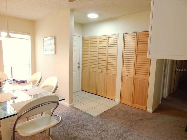 dining area with light carpet, baseboards, and a textured ceiling