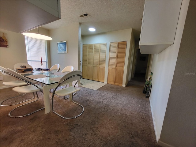 dining room featuring a textured ceiling, baseboards, visible vents, and light colored carpet