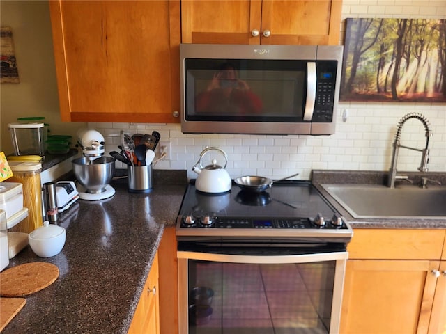 kitchen with brown cabinetry, appliances with stainless steel finishes, decorative backsplash, and a sink