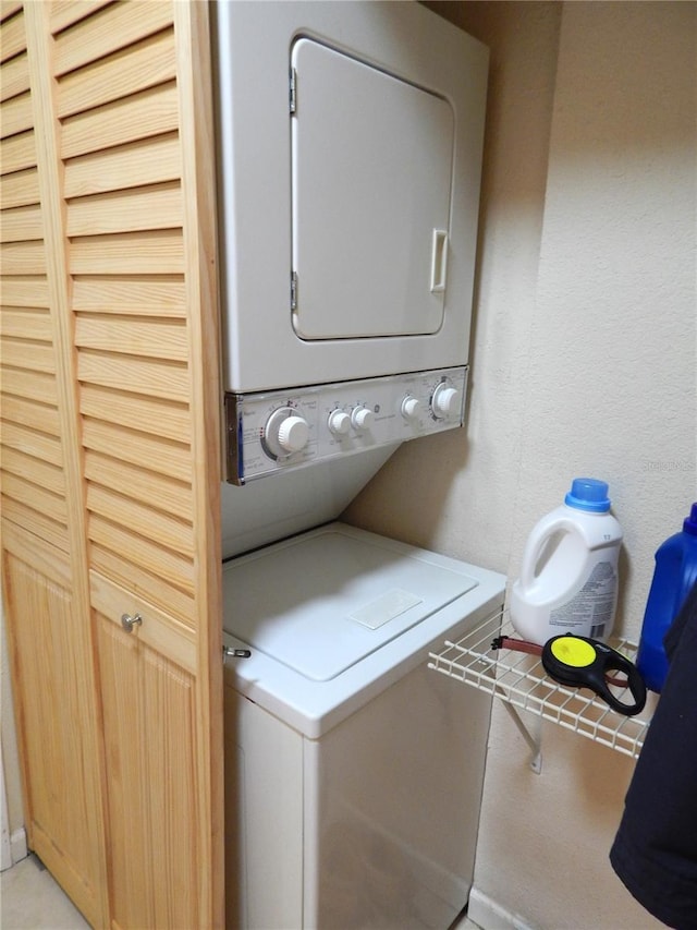 laundry area with a textured wall, laundry area, and stacked washer and clothes dryer