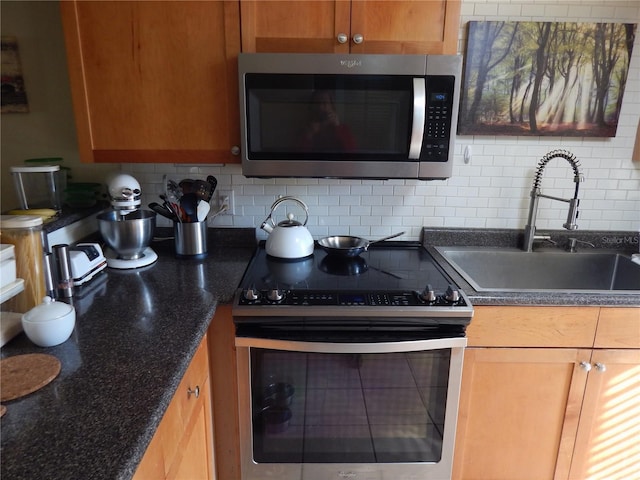 kitchen featuring appliances with stainless steel finishes, brown cabinetry, a sink, and tasteful backsplash