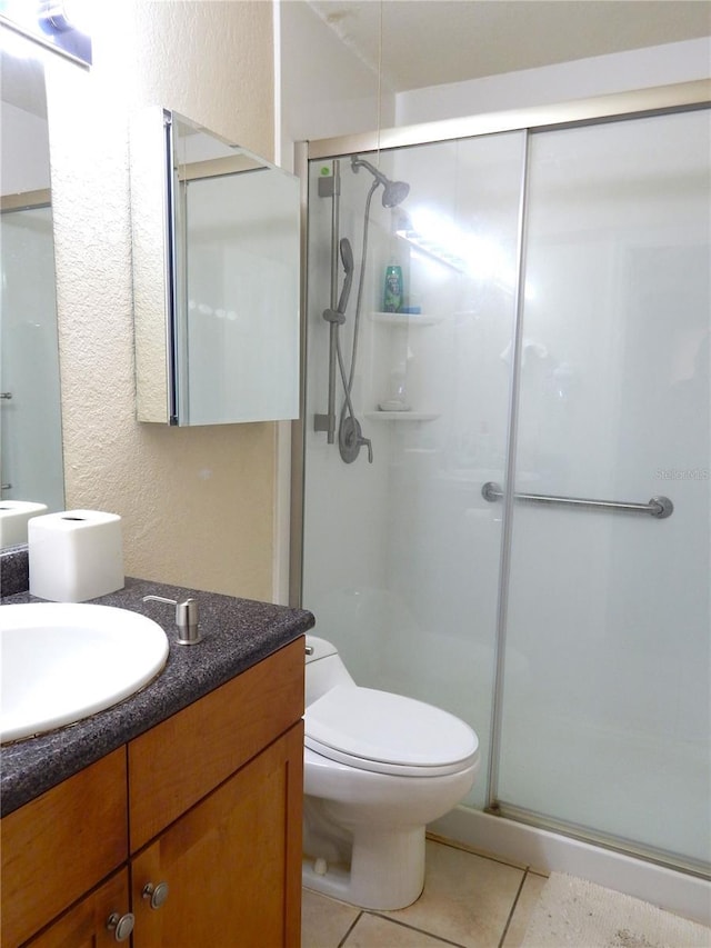 full bath with toilet, a stall shower, tile patterned flooring, and vanity