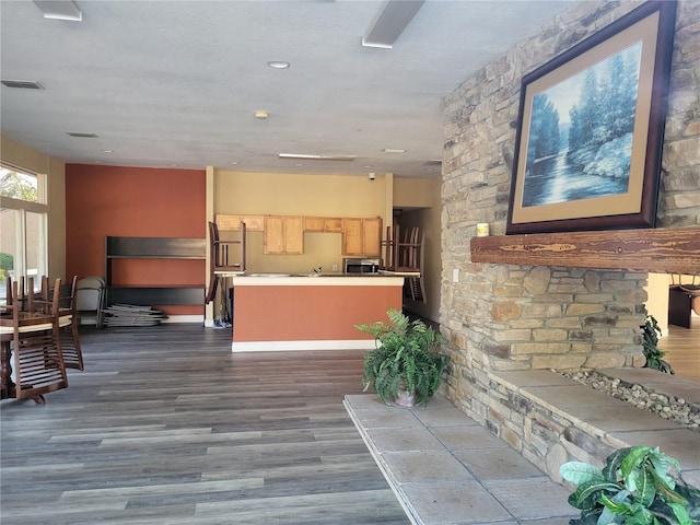 kitchen with dark wood finished floors, stainless steel microwave, visible vents, light brown cabinets, and a kitchen island