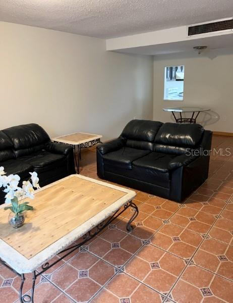 living area featuring tile patterned floors, visible vents, and a textured ceiling