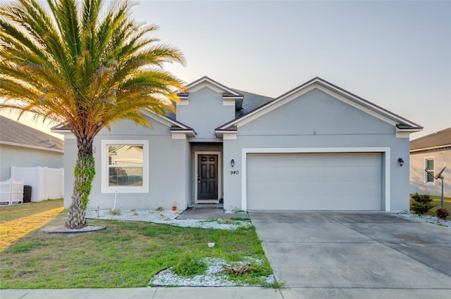 view of front facade with stucco siding, a front yard, fence, a garage, and driveway