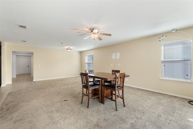 dining room with a ceiling fan, light colored carpet, visible vents, and baseboards