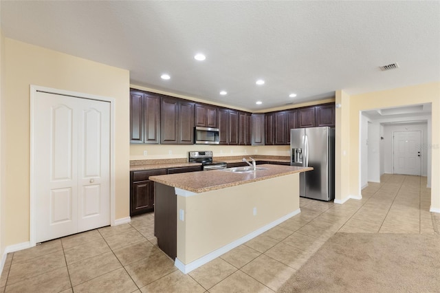 kitchen with light tile patterned floors, dark brown cabinetry, a sink, visible vents, and appliances with stainless steel finishes