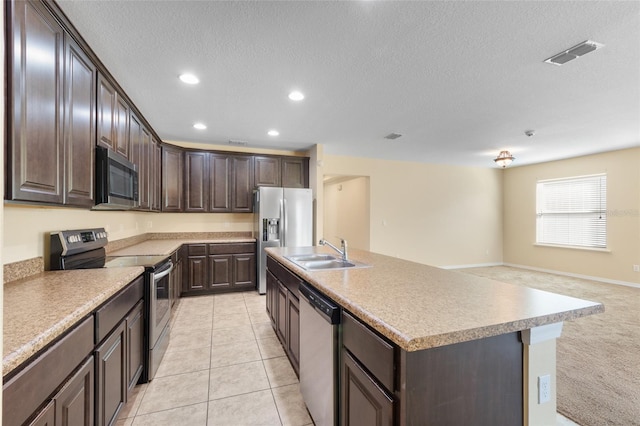 kitchen with a center island with sink, stainless steel appliances, visible vents, a sink, and dark brown cabinets