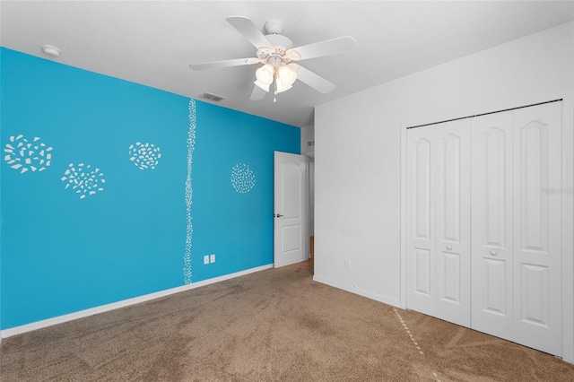 unfurnished bedroom featuring baseboards, visible vents, ceiling fan, carpet floors, and a closet