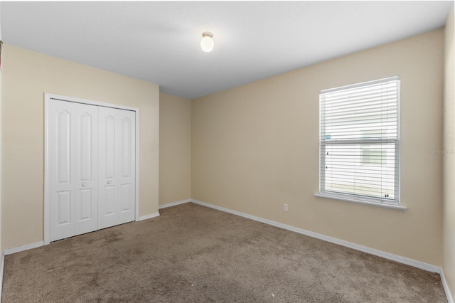 unfurnished bedroom featuring carpet floors, baseboards, and a closet