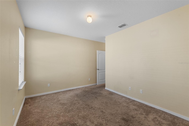 carpeted spare room with visible vents, a textured ceiling, and baseboards