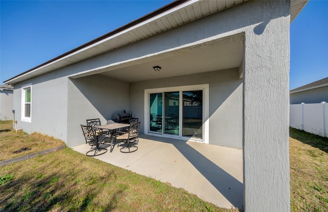 rear view of house with a patio area, fence, a lawn, and stucco siding