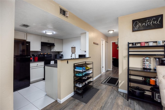 kitchen featuring dark countertops, black appliances, visible vents, and under cabinet range hood