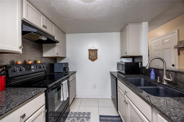 kitchen featuring light tile patterned flooring, a sink, under cabinet range hood, black appliances, and dark stone counters