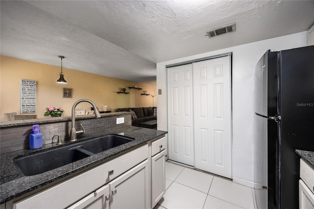 kitchen with visible vents, tasteful backsplash, a sink, light tile patterned floors, and freestanding refrigerator