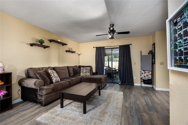 living room featuring dark wood finished floors, baseboards, and a ceiling fan