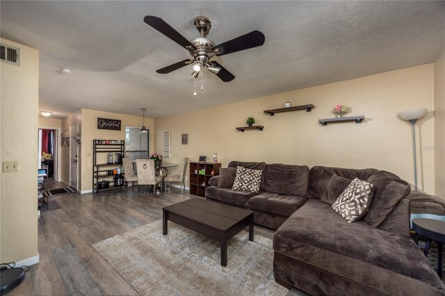 living area featuring baseboards, visible vents, wood finished floors, and ceiling fan