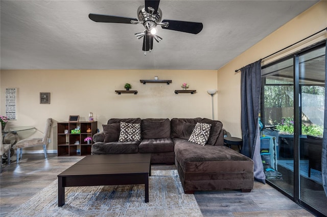 living area with baseboards, wood finished floors, and a ceiling fan