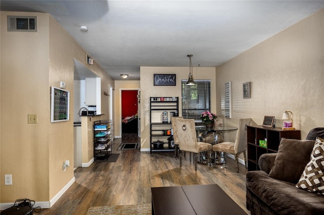 living area with dark wood finished floors, baseboards, and visible vents