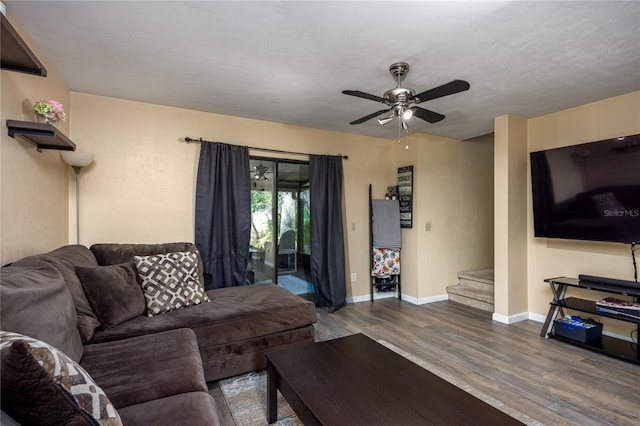 living area with baseboards, dark wood-style flooring, stairway, and a ceiling fan
