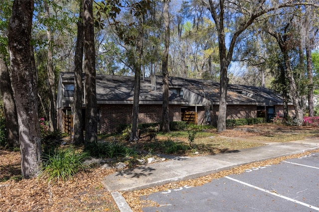 mid-century inspired home featuring uncovered parking and brick siding