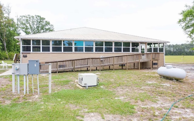 rear view of property featuring a wooden deck, a sunroom, and metal roof