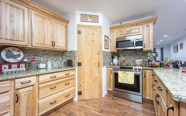 kitchen featuring light stone counters, light brown cabinets, stainless steel appliances, light wood-type flooring, and backsplash