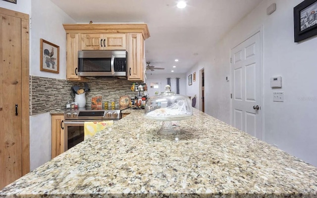 kitchen featuring tasteful backsplash, light stone countertops, light brown cabinetry, stainless steel appliances, and a ceiling fan