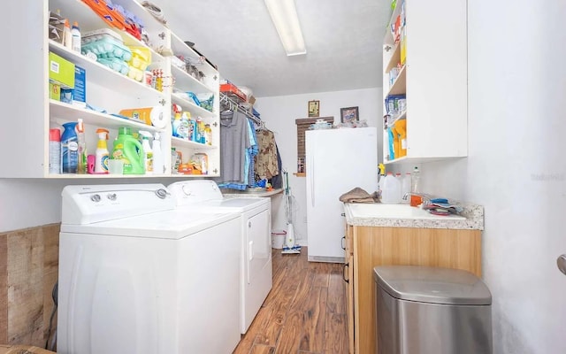 laundry room featuring a sink, wood finished floors, cabinet space, and washing machine and clothes dryer