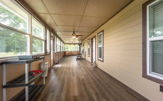 unfurnished sunroom featuring a drop ceiling and ceiling fan