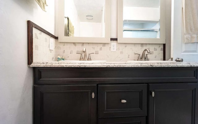 full bathroom featuring decorative backsplash, double vanity, and a sink