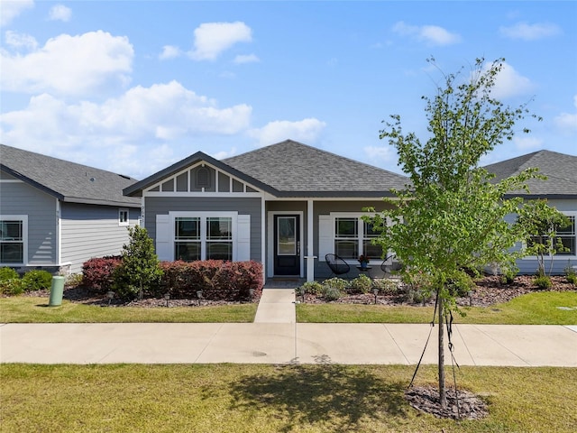 view of front of home with a shingled roof, board and batten siding, and a front yard