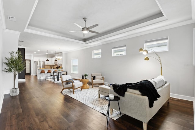 living area featuring dark wood-type flooring, a tray ceiling, visible vents, and baseboards