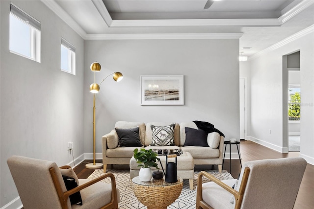 living room with ornamental molding, a wealth of natural light, a raised ceiling, and wood finished floors